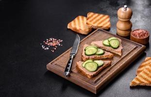 Delicious fresh sandwich with chicken liver pate with crispy toast, butter and cucumber photo
