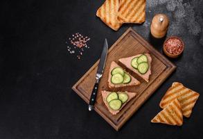 Delicious fresh sandwich with chicken liver pate with crispy toast, butter and cucumber photo