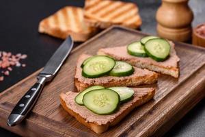 Delicious fresh sandwich with chicken liver pate with crispy toast, butter and cucumber photo