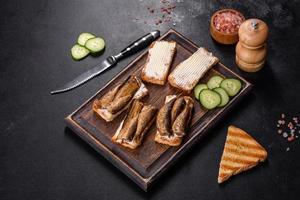 Delicious fresh sandwich with sprats with crispy toast, butter and cucumber photo