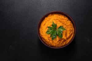Squash caviar with garlic and tomatoes in a rustic bowl on a dark background photo