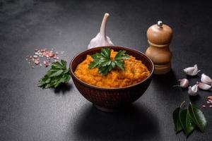 Squash caviar with garlic and tomatoes in a rustic bowl on a dark background photo