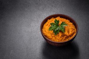 Squash caviar with garlic and tomatoes in a rustic bowl on a dark background photo