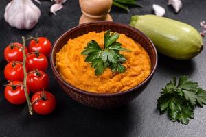 Squash caviar with garlic and tomatoes in a rustic bowl on a dark background photo
