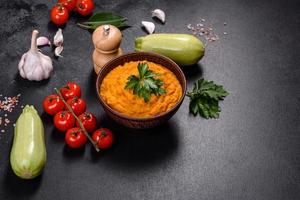 Squash caviar with garlic and tomatoes in a rustic bowl on a dark background photo