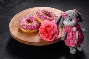 Beautiful knitted rabbit toy with doughnuts with pink glaze and coloured sprinkle photo