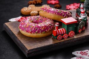 A beautiful doughnut with pink glaze and colored sprinkle on a christmas table photo