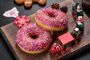 A beautiful doughnut with pink glaze and colored sprinkle on a christmas table photo