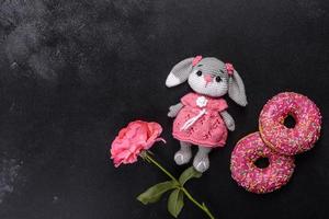 Beautiful knitted rabbit toy with doughnuts with pink glaze and coloured sprinkle photo