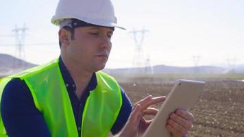 Ingenieur arbeitet mit Tablet auf Ackerland. landwirtschaftliche Bewässerung wird durchgeführt und der Ingenieur arbeitet am Tablet. moderne und technologische Landwirtschaft. video