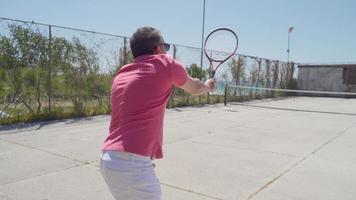 l'uomo che gioca a tennis. uomo che gioca a tennis con la donna in tempo soleggiato. fare un tiro di partenza nel tennis. video