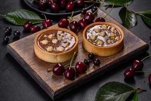 Delicious fresh nougat and nut tart with fresh berries on a wooden cutting board photo