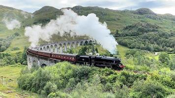 glenfinnan en escocia en el reino unido en agosto de 2021. una vista del viaducto de glenfinnan que muestra un tren de vapor que pasa sobre él foto