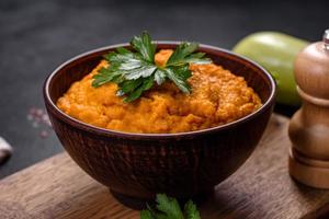 Squash caviar with garlic and tomatoes in a rustic bowl on a dark background photo