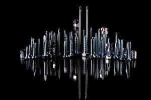 A fantastic city made of bolts, nuts, screws and self-cuts on a black background with reflection photo