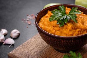 Squash caviar with garlic and tomatoes in a rustic bowl on a dark background photo