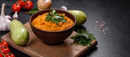 Squash caviar with garlic and tomatoes in a rustic bowl on a dark background photo