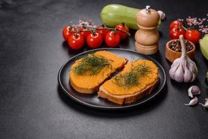 Delicious squash caviar sandwiches on a dark concrete background, healthy breakfast photo