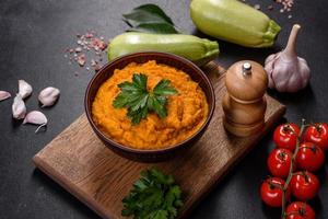 Squash caviar with garlic and tomatoes in a rustic bowl on a dark background photo