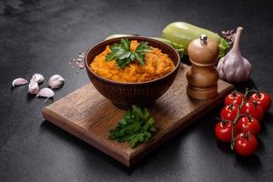 Squash caviar with garlic and tomatoes in a rustic bowl on a dark background photo