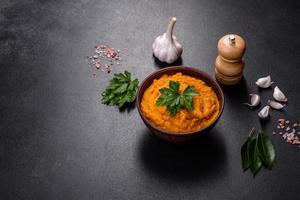 Squash caviar with garlic and tomatoes in a rustic bowl on a dark background photo