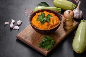 Squash caviar with garlic and tomatoes in a rustic bowl on a dark background photo