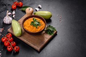 Squash caviar with garlic and tomatoes in a rustic bowl on a dark background photo