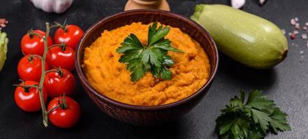 Squash caviar with garlic and tomatoes in a rustic bowl on a dark background photo