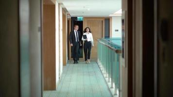 femme d'affaires et homme d'affaires marchant dans le couloir. homme d'affaires et femme d'affaires détenant un ordinateur portable marchent dans le couloir. video