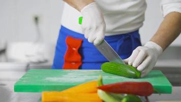 o cozinheiro está cortando pepinos. confecção de saladas. o chef pega os pepinos que ele moldou depois de mergulhá-los na água. video