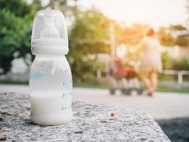 biberón de leche en la mesa de piedra sobre la madre con fondo de carro de bebé foto