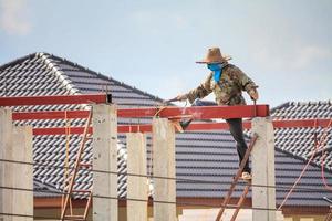 welder workers installing steel frame structure of the house roof at building construction site photo