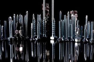 A fantastic city made of bolts, nuts, screws and self-cuts on a black background with reflection photo