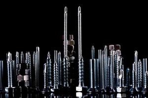 A fantastic city made of bolts, nuts, screws and self-cuts on a black background with reflection photo
