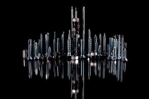 A fantastic city made of bolts, nuts, screws and self-cuts on a black background with reflection photo