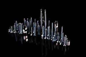 A fantastic city made of bolts, nuts, screws and self-cuts on a black background with reflection photo