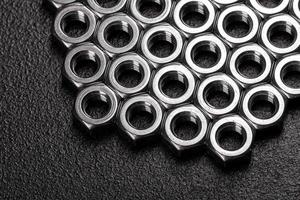 Metal steel nuts laid in composition on a dark table photo