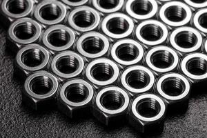 Metal steel nuts laid in composition on a dark table photo