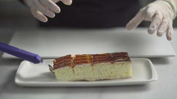 Chef and tiramisu dessert. The chef with his gloved hands arranges the trilece with caramel sauce desserts. video