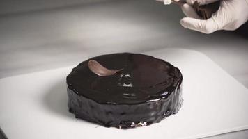 chef che fa torta, salsa al cioccolato. lo chef mette le gocce di cioccolato sulla torta. decora la torta. video