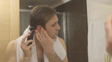 uomo che si rade la barba con la macchina. in bagno, l'uomo si rade con la macchina. si sta radendo la barba. video