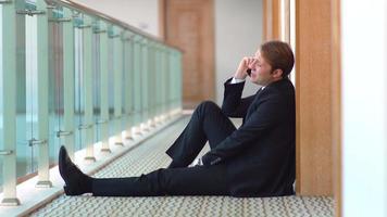 Businessman talking on the phone. Corridor. Businessman sitting on the floor in the hallway talking on the phone. video