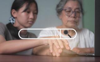 Granddaughter is teaching Grandma to use a laptop computer to search the Internet, photo