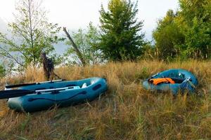 Two rubber boats with fishing tackle in the early morning during the fog, parked on the banks of the river. photo