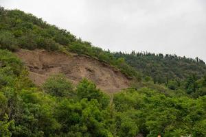 A mountain landslide in an ecologically dangerous zone, the fall of large layers of earth blocking the road. Soil under erosion conditions. photo