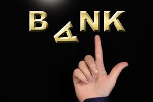 A finger points to the word Bank, made of miniature three-dimensional letters, with the letter A falling, on a black background.