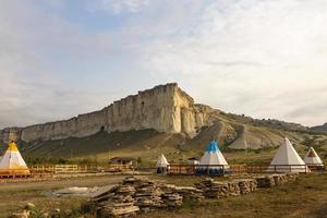 Great view of the tipi in the field with the American rocky mountain landscape in the background. photo