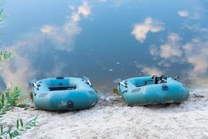 Two rubber boats with fishing tackle in the early morning during the fog, parked on the banks of the river. photo