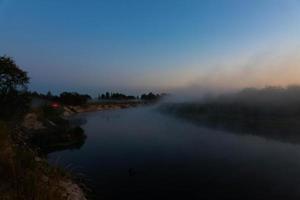 mañana nublada en un río europeo con hierba verde fresca bajo el sol. los rayos del sol a través del árbol. foto