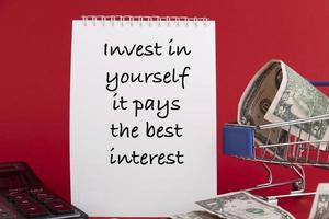 Invest in yourself it pays the best interest, the text of the is written in a white notepad red background. photo